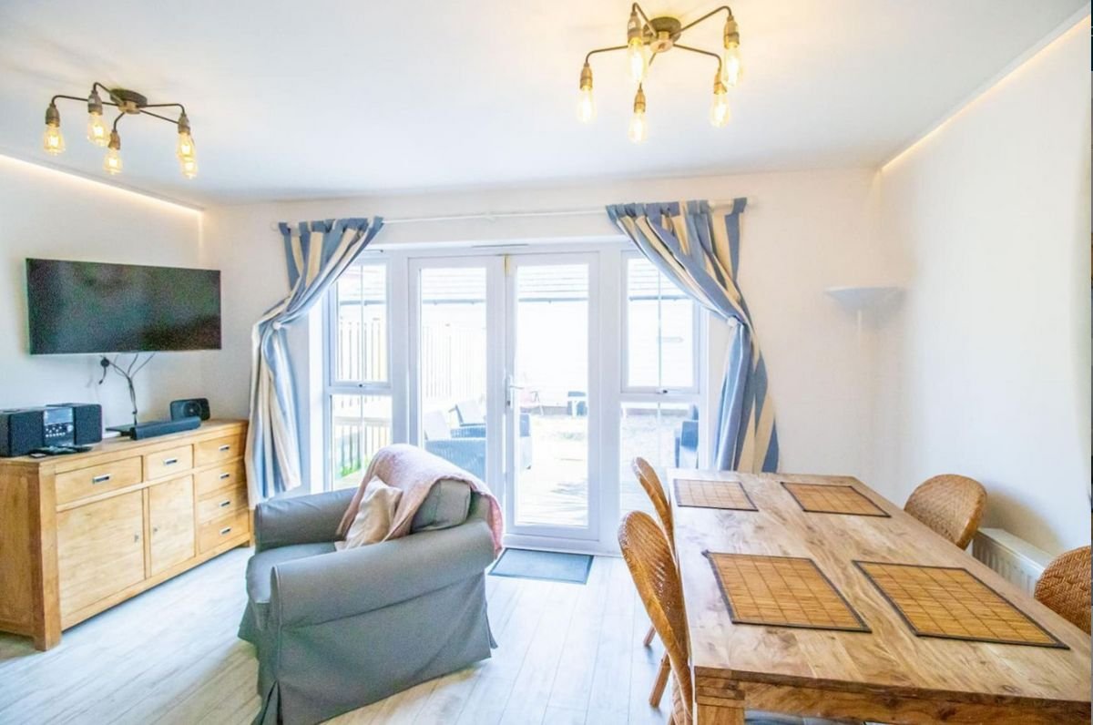 Timber dining table and sofa in the light-filled lounge of Beachside Cottage, Camber Sands