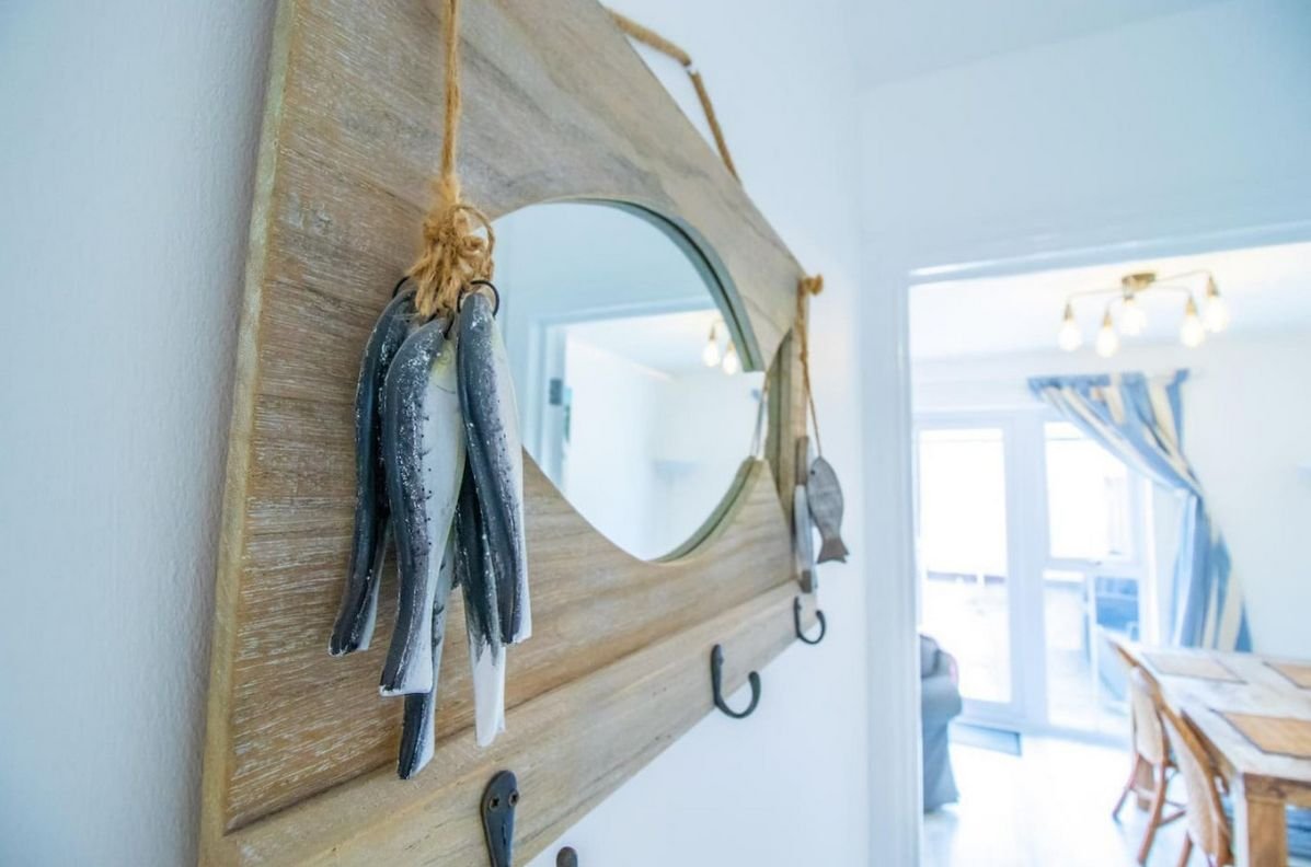 Driftwood-framed mirror and feather detail in the hallway of Beachside Cottage