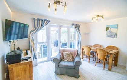 Living room at Beachside Cottage with an armchair, sofa and French windows to the garden