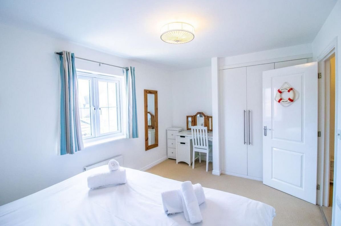 Twin bedroom at Beachside Cottage with wardrobe, dressing table and lifebuoy wall decoration